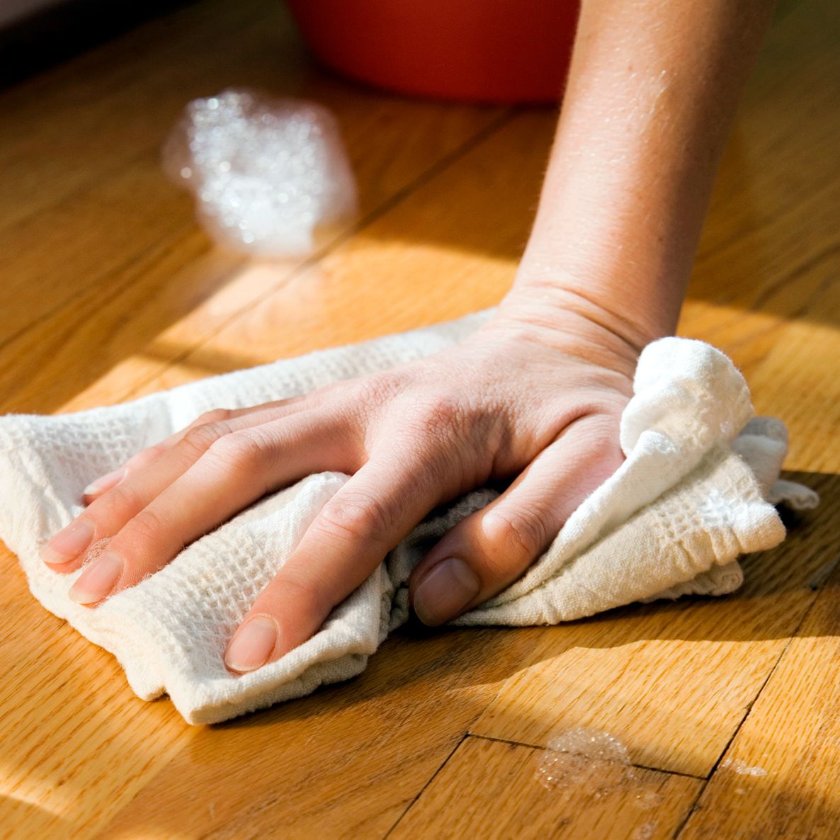 person wiping down wood floors with rag