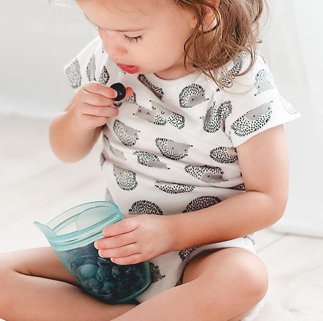 toddler with blueberries in a zip top food storage container