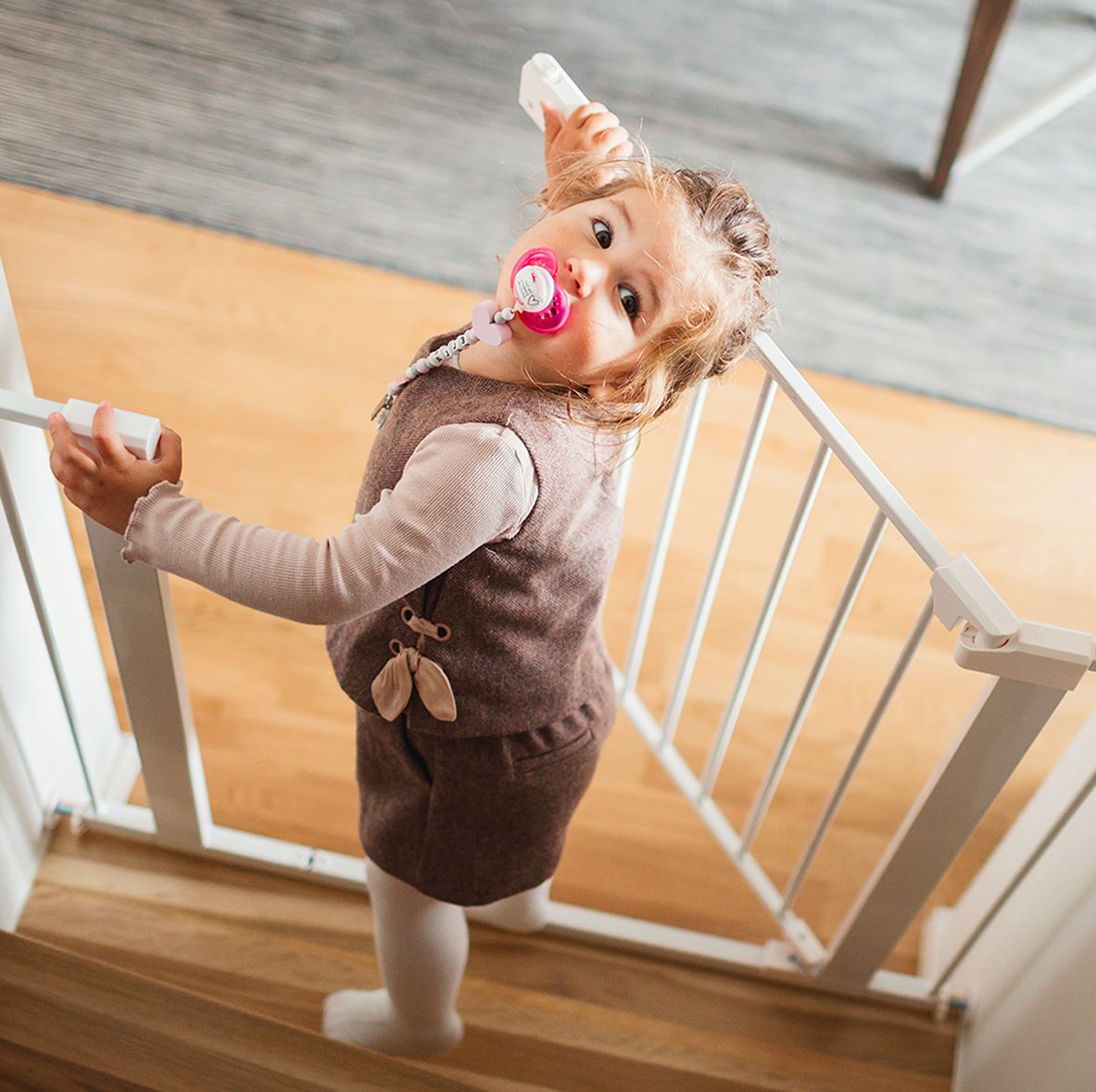 toddler looking up the stairs while opening baby gate