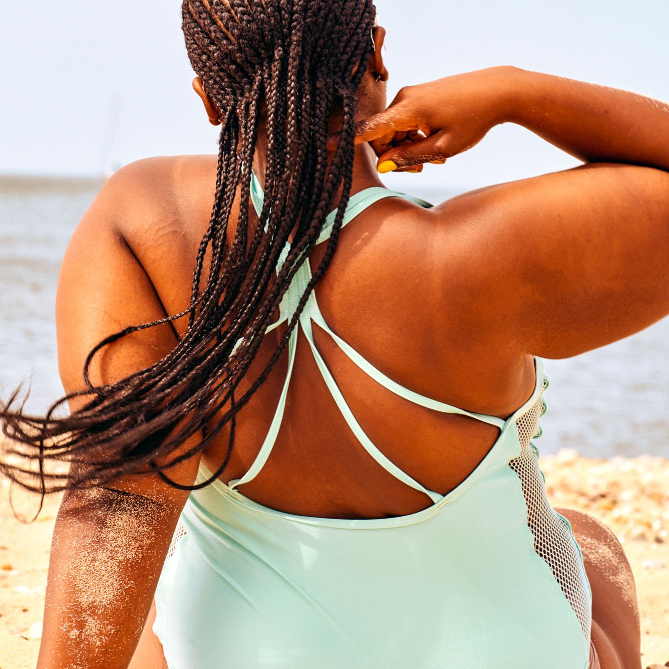 woman sitting on beach in blue swimsuit