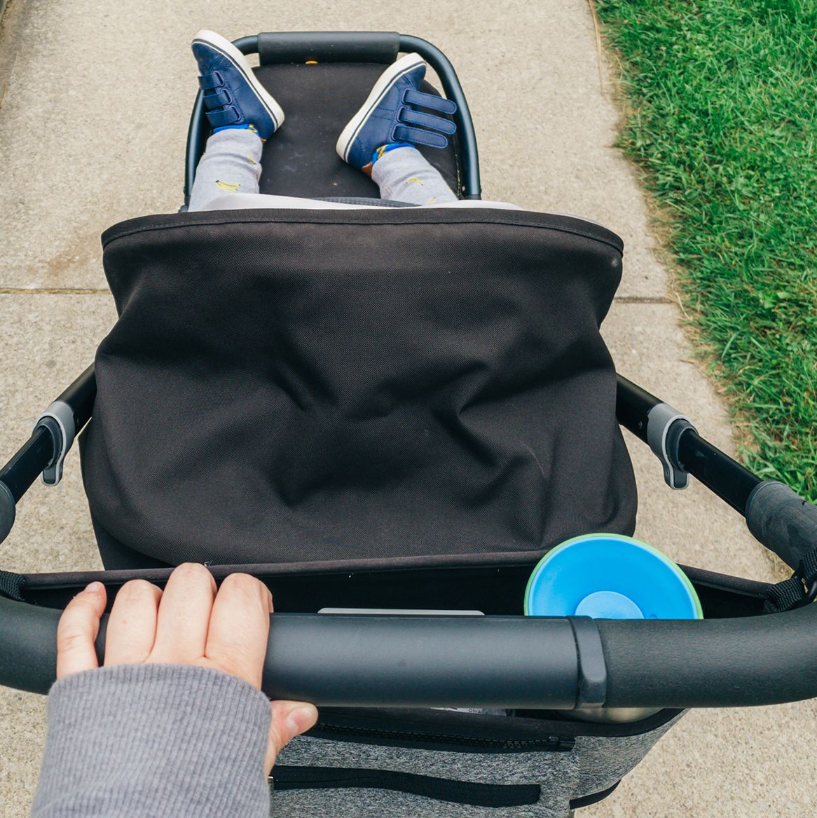 person pushing stroller with organizer hanging off handle