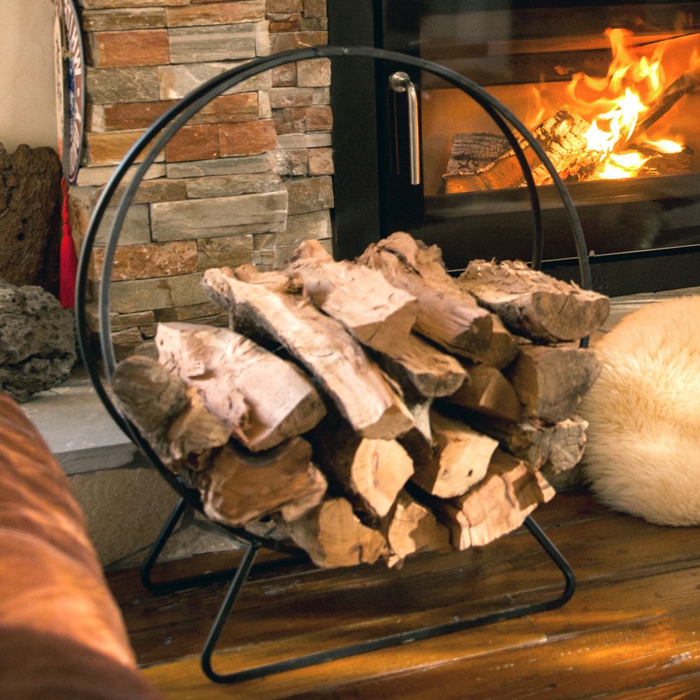 circular iron firewood rack in front of fireplace with sheepskin rug and pinecones