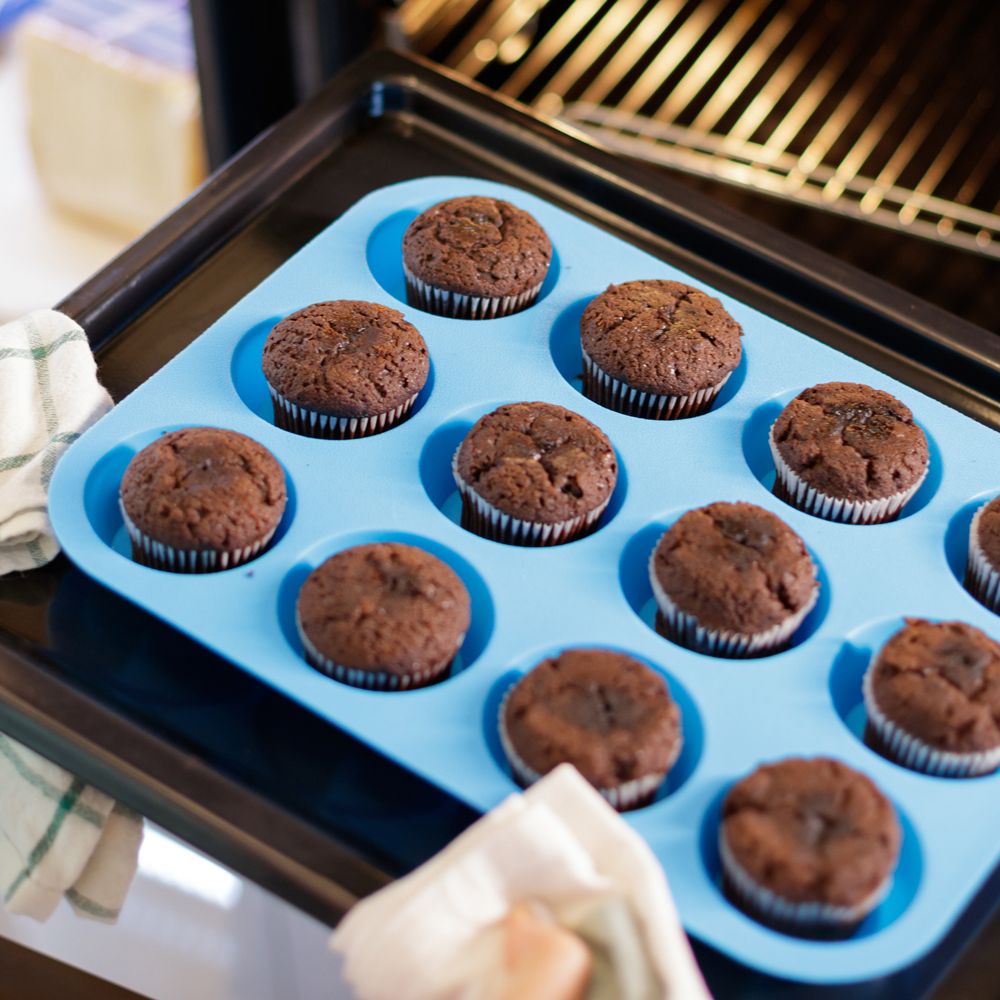 chocolate cupcakes in blue silicone muffin tin going into oven