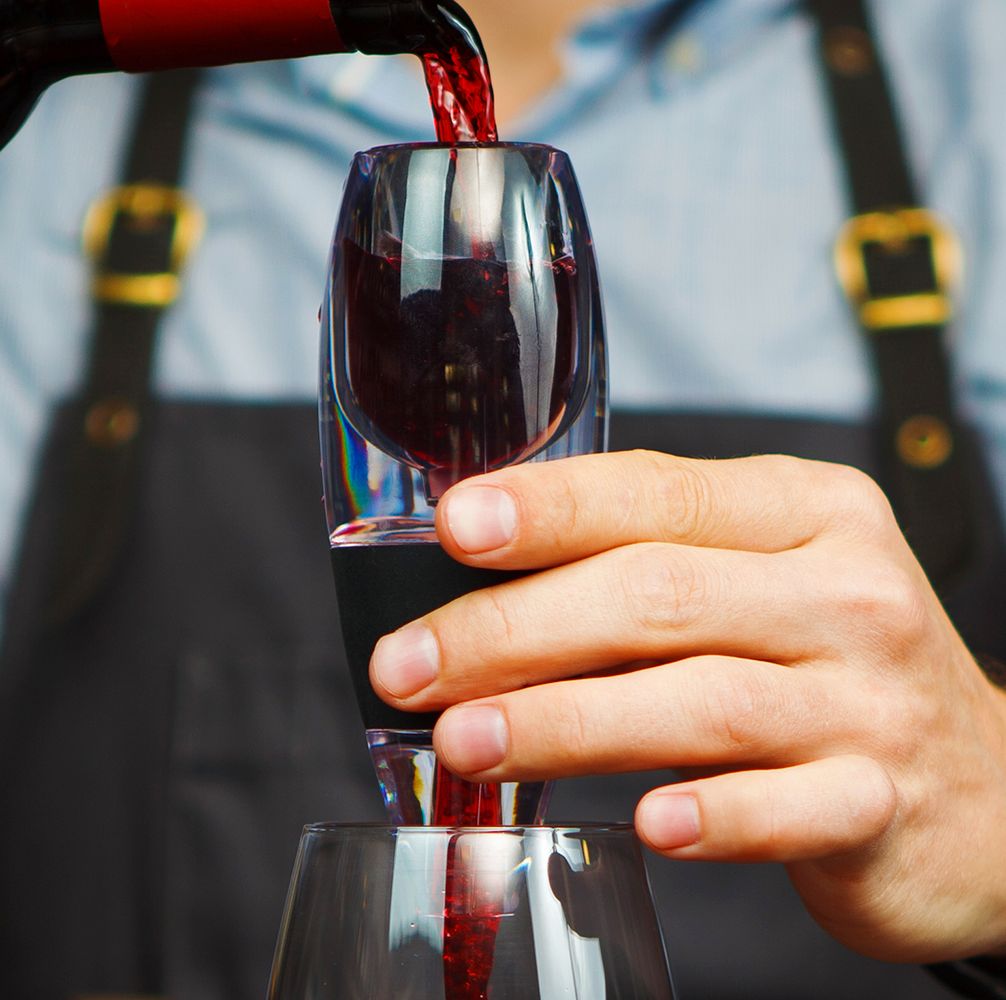 man in apron pouring red wine through an aerator